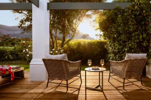 a patio with two chairs and a table with wine glasses at Steenberg Hotel & Spa in Tokai