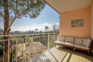 a couch sitting on a balcony with a tree at ElTufeto Apartment - Parking and Terrace in Grado-Pineta
