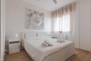 a white bedroom with a white bed and a window at ElTufeto Apartment - Parking and Terrace in Grado-Pineta