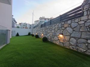 a stone wall with lights on the side of a yard at ALTA MARE in Nea Peramos
