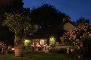 a house with people sitting in the yard at night at Willow Cottage in Studland