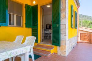 a yellow house with green shutters and a table and chairs at Appartamento Il Mare Dalla Terrazza in Rio nellʼElba