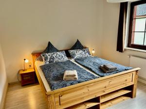 Schlafzimmer mit einem Holzbett mit blauer Bettwäsche und Kissen in der Unterkunft Große Ferienwohnungen 5 - 8 "Pumphut's Scheune" in Lengenfeld