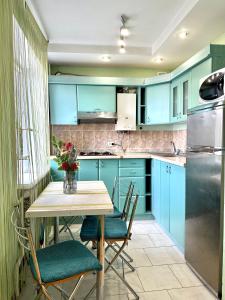 a kitchen with blue cabinets and a table with chairs at Apartments in the city centre, near the park in Rivne