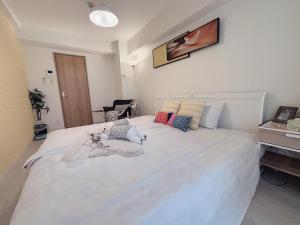 una camera da letto con un grande letto bianco con cuscini di OSAKA SUNSHINE TOWER92 ad Osaka