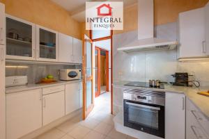 a kitchen with white cabinets and a stove at Sal de Mar - Casa La Fosca in Palamós