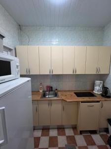 a kitchen with white cabinets and a sink and a microwave at Alutaguse Tervisespordikeskuse Päikesemaja in Vasavere