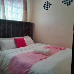 - un lit avec des oreillers roses et blancs dans l'établissement Phyl, à Kitengela 
