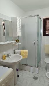 La salle de bains blanche est pourvue d'une douche et d'un lavabo. dans l'établissement Apartment Miro, à Matulji
