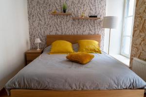 una camera con un letto con due cuscini gialli di App cosi Ile Saint Laurent Chalon Sur Saone a Chalon-sur-Saône