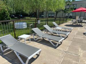three lounge chairs and a table and an umbrella at Ramada by Wyndham Newark/Wilmington in Newark