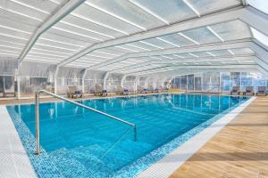 een groot zwembad met blauw water in een gebouw bij Jupiter Algarve Hotel in Portimão