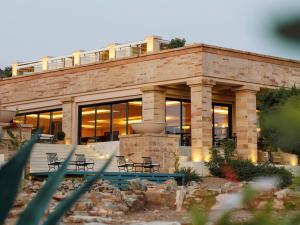 um edifício com mesas e cadeiras em frente em Cape Sounio Grecotel Boutique Resort em Sounio