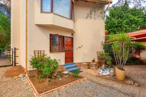 Cottage on Pipers في Sandton: منزل فيه باب احمر وبعض النباتات