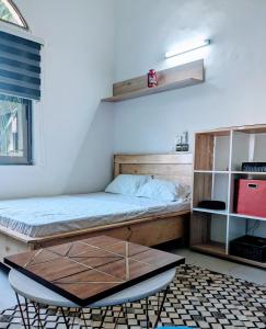 1 dormitorio con cama, mesa y estanterías en Residence Nenuphar en Abomey-Calavi