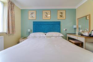 a bedroom with a large white bed with a blue headboard at The Bridge House; BW Signature Collection in Ferndown