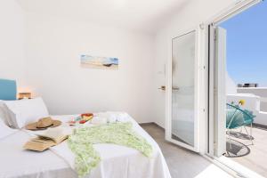 a white room with a bed with a glass door at Helen Beach Front Luxury Villas in Kastraki Naxou