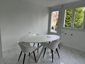 ein weißes Esszimmer mit einem weißen Tisch und Stühlen in der Unterkunft appartement jacuzzi in Le Havre
