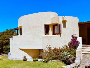 a house with a curved facade with flowers at Vistamare Cala Granu in Porto Cervo