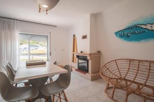 a dining room with a table and chairs and a fireplace at Paredes Surf House in Pataias