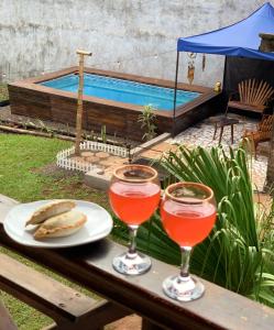 dois copos de vinho sentados numa mesa ao lado de uma piscina em Terra bela em Puerto Iguazú