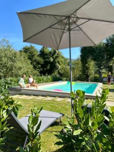 an umbrella and two people sitting by a swimming pool at La Sovrana dei Cimini in Bagnaia