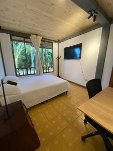 - une chambre avec un lit et une télévision murale dans l'établissement Casa Vélez: habitación natural, à Villamaría