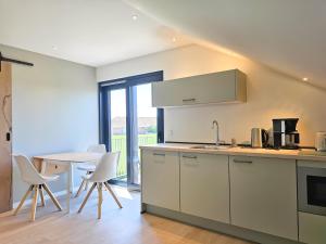 Una cocina con gabinetes blancos y una mesa con sillas. en Appartement 'Advenco' AK07 Aagtekerke, en Aagtekerke