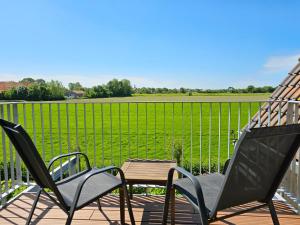 2 sillas y una mesa en una terraza con un campo en Appartement 'Advenco' AK07 Aagtekerke, en Aagtekerke