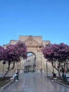 un edificio con alberi con fiori rosa di fronte di Stella del Barocco a Lecce