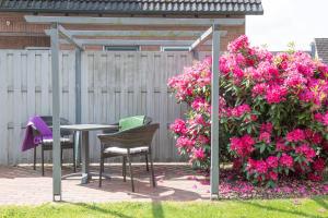 een patio met een tafel en stoelen en roze bloemen bij Seeluft in Cuxhaven