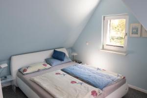 een kleine slaapkamer met een bed met blauwe muren en een raam bij Seeluft in Cuxhaven +24 foto's