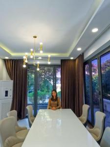 a woman sitting at a table in a room with windows at Benzen villa in Nha Trang +267 photos