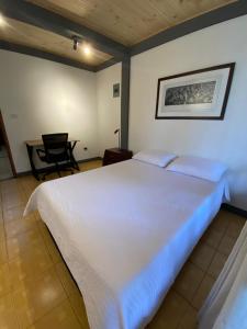 een groot wit bed in een kamer met een stoel bij Casa Vélez: habitación natural in Villamaría