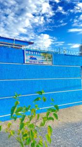 un mur bleu avec un panneau indiquant hospitalitzitzitzitzitzitzitz dans l'établissement Hostel Pé na Praia Itanhaém, à Itanhaém