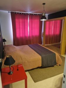 - une chambre dotée d'un lit avec des rideaux roses et une table rouge dans l'établissement Le Cocoon De Sacha, à Avize