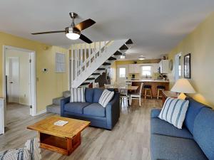 a living room with two blue couches and a staircase at Happy Days in Surf City