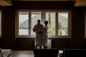 a bride and groom standing in front of a large window at Hotel Del Lago 1934 & SPA in Piediluco