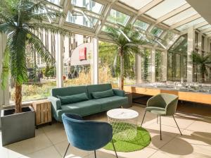 - un salon avec un canapé et des chaises dans une véranda dans l'établissement ibis Paris 17 Clichy-Batignolles, à Paris