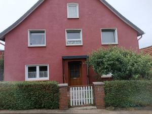 a red house with a white fence in front of it at Petra's Ferienunterkunft Barsinghausen in Barsinghausen