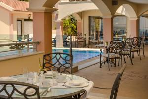 a restaurant with a table and chairs next to a pool at Belle View Hotel - Sea View & Sunset in Mánganos