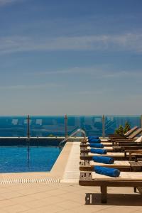 a row of benches with blue infront of a swimming pool at Belle View Hotel - Sea View & Sunset in Mánganos