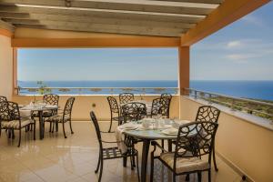 a restaurant with tables and chairs on a balcony at Belle View Hotel - Sea View & Sunset in Mánganos