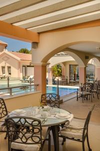 a patio with tables and chairs next to a swimming pool at Belle View Hotel - Sea View & Sunset in Mánganos