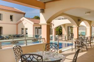 a patio with tables and chairs next to a swimming pool at Belle View Hotel - Sea View & Sunset in Mánganos