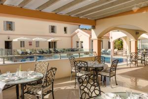 a patio with tables and chairs and a pool at Belle View Hotel - Sea View & Sunset in Mánganos