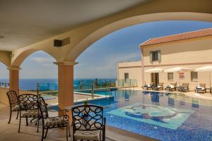 a swimming pool with chairs and a view of the ocean at Belle View Hotel - Sea View & Sunset in Mánganos