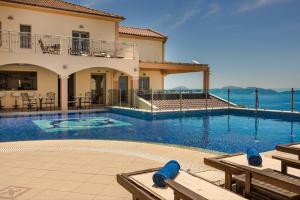 a house with a swimming pool in front of a house at Belle View Hotel - Sea View & Sunset in Mánganos