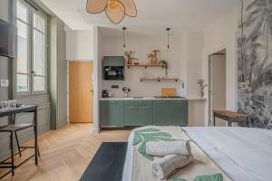a kitchen with green cabinets and a bed in a room at Le Félix Appart'Hotel, centre ville Romans-sur-Isère in Romans-sur-Isère