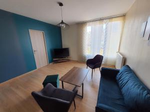 Una sala de estar con un sofá y sillas y una mesa. en Appartement 6 couchages environnement paisible, en Saint-Étienne-du-Rouvray